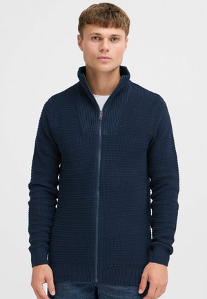 Marine blå zip-sweater lavet af tekstureret strikstof med høj krave. Har ribbede manchetter og lige snit.