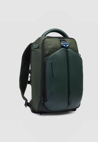 Zaino verde con corpo in tessuto resistente, manico superiore arrotondato e pannello frontale liscio. Dotato di chiusure lampo e tasche laterali in rete per gli accessori.