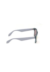 Sonnenbrille mit grauem Rahmen, grünen Akzenten und strukturierten grauen Bügeln. Die Gläser haben einen leichten Farbton. Enthält Logodetails auf den Bügeln.