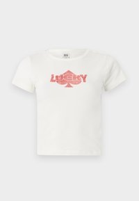 Biela bavlnená tričko s krátkymi rukávmi, s ružovou trblietavou grafikou slova "LUCKY" a tvarom srdca pod ním.