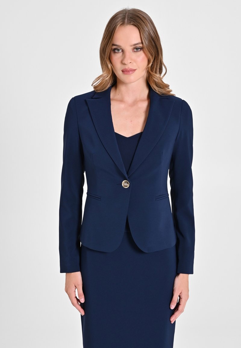 Navyblazer aus glattem Stoff, taillierte Passform mit geschlitzten Revers, ein einzelner metallener Knopfverschluss und zwei Fronttaschen.