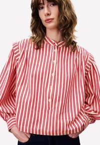 Rood en wit gestreepte shirt met hoge kraag, met een knoopsleep voor, gebloemde mouwen en een losse pasvorm. Van katoen.