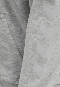 Grå hoodie med en mjuk textur, som har en känguruficka och en ärmdesign med tre upphöjda grå chevronformer.