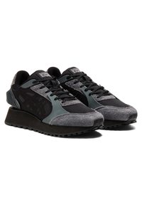 Sneaker nere e grigie con una tomaia texturizzata, materiali in suede e mesh, una suola spessa e un dettaglio di laccio a contrasto.