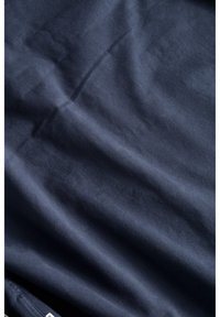 Tessuto blu scuro con una superficie liscia, che mostra leggere pieghe e grinze, indicando un materiale leggero e morbido. Nessun motivo o dettaglio visibile.