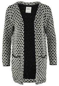 Stickad cardigan med ett svart och vitt geometriskt mönster, öppen fram, långa ärmar och två framfickor. Mjuk textur med en avslappnad passform.