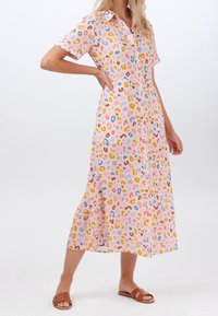 Kauluspaita, lyhythihainen mekko vaaleanpunaisena, jossa on monivärinen eläinkuoski. Valmistettu kevyestä kankaasta, polvipituinen ja napitus edessä.