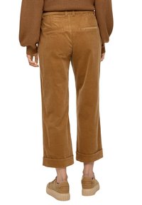 Bruine corduroy broek met een relaxte pasvorm, cropped lengte en opgerolde manchetten. Beschikt over twee achterzakken en een soepele textuur.