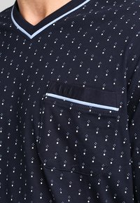 Camiseta de algodón de color azul marino con cuello en V, con un patrón de puntos en blanco y azul claro. Incluye un bolsillo en el pecho con acentos en azul claro.