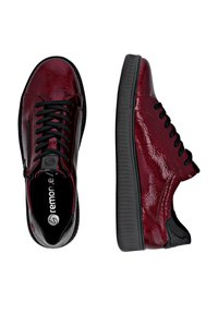 Baskets en cuir verni rouge et noir avec une texture lisse, un design à lacets et un bout arrondi. Semelle en caoutchouc crantée pour une meilleure adhérence.