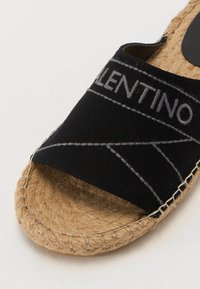 Sandale slide negre din material textil, cu o talpă texturată din jute. Cusuți gri și logo-ul "Valentino" pe curea.