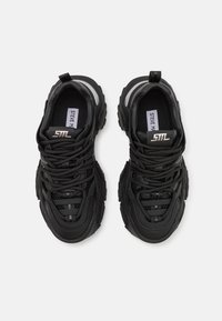 Černé sportovní tenisky s kombinací hladkých a texturovaných materiálů, s mezivrstvami z polyesterové síťoviny, výraznými tkaničkami a stříbrnými akcenty.