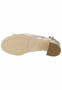 Metallisk sølv højhælet sko med en glat tekstur, rund tå, justerbar rem og en beige gummisål med subtile mønstre.