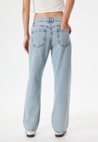 Jeans de mezclilla de ancho amplio en azul claro con una cintura alta, que cuentan con dos bolsillos traseros y una textura deslavada. El dobladillo está ligeramente acolchado para dar estructura.