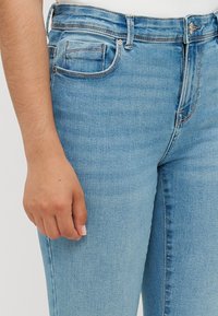 Lichtblauwe denim jeans met een fitted snit, voorzien van een knoop- en ritssluiting, vijf zakken en subtiele vervaging op de stof.
