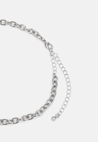 Silberne Metallkette mit großen, ineinandergreifenden ovalen Gliedern und einem Karabinerverschluss. Verstellbare Kette mit kleinem Kugelakzent am Ende.