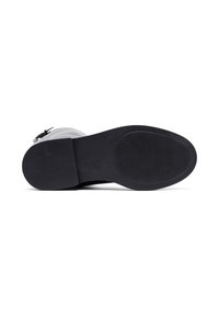 Sole di scarpa nera con superficie in gomma testurizzata, dotata di un tacco basso e a blocco e un bordo liscio e arrotondato. Design semplice e funzionale.