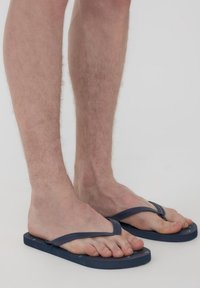 Infradito blu navy con una soletta texturizzata, dotati di cinturini sottili e suola piatta. Dita dei piedi visibili e tono della pelle chiaro.