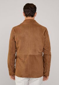 Chaqueta de ante marrón con un acabado texturizado, con un cuello clásico y corte recto, exhibida desde atrás.