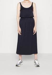 Granatowa maxi sukienka z okrągłym dekoltem i elastyczną talią. Noszona z srebnymi butami sportowymi z czarnymi akcentami i białymi sznurówkami.