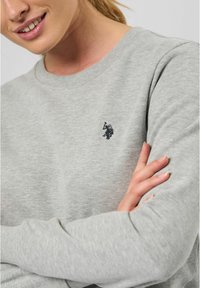 Grijze sweatshirt van een zachte katoenmix. Heeft een ronde hals, geribbelde manchetten en een klein geborduurd logo op de borst.