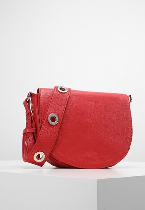 Rød læder crossbody-taske med rundet klap og bred rem med store sølvnitter, vist på hvid sokkel mod ensfarvet baggrund.