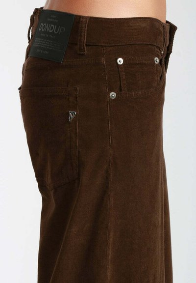 Pantaloni in corduroy marrone con una superficie testurizzata, dotati di cinque tasche e accessori in tono argento. Un'etichetta in tessuto è attaccata alla vita.