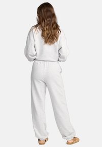 Grauer Pullover und passende Jogginghose aus weichem Material mit elastischem Bund, die eine lockere Passform und geraffte Bündchen hat.