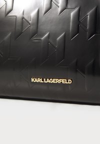 Borsa in pelle nera impresso con motivi geometrici, una texture liscia e una placca dorata con il logo "KARL LAGERFELD".