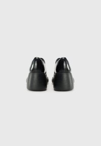 Black leather shoes with a rounded toe and chunky, textured black heel. Smooth finish with minimal detailing, viewed from the back.