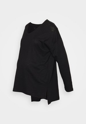 Haut de maternité noir à manches longues, ample, avec un col en V et des fentes sur les côtés, présenté sur un fond blanc uni.