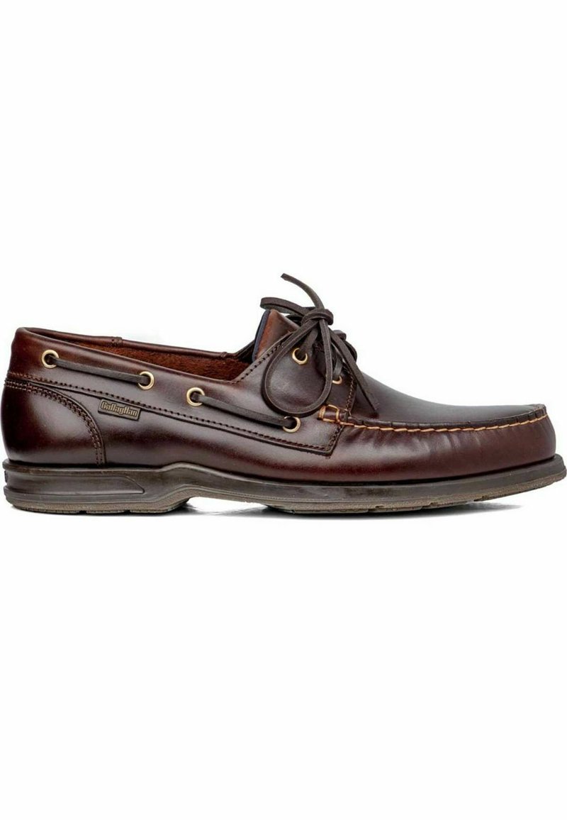 Zapato de barco de cuero marrón con punta redondeada, detalles de cordones, ojales dorados y una suela texturizada para mayor agarre. Presenta acentos de costura visibles.