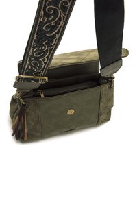 Borsa in pelle verde oliva con texture trapuntata, dotata di un compartimento con cerniera, nappine decorative e una tracolla in tessuto stampato.