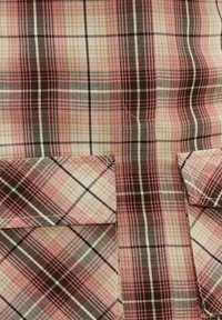 Tissu à carreaux rose, beige et noir avec deux poches à rabat assorties, présentant un motif à carreaux diagonaux et verticaux.