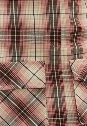 Tissu à carreaux rose, beige et noir avec deux poches à rabat assorties, présentant un motif à carreaux diagonaux et verticaux.