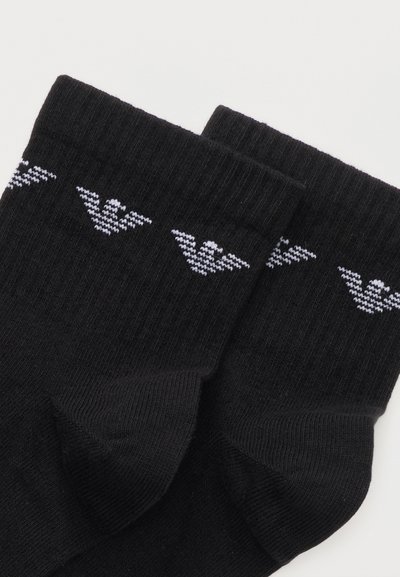 Ζευγάρι μαύρες ριγωτές κάλτσες με λευκά σχέδια πουλιών κοντά στη μανσέτα, τοποθετημένες επίπεδα σε λευκό φόντο.