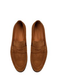Mocasines de ante marrón con punta redondeada, presentando una costura decorativa y una banda ancha en la parte superior con un sutil detalle de corte.