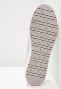 Podeszwa jasnoszarego sportowego buta z fakturowanym bieżnikiem i widocznym rozmiarem 37 na jednolitym białym tle.