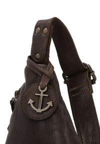 Cinghia di pelle marrone scuro con distintivo in metallo ad ancora impresso con "HARBOUR 2nd" attaccato vicino a doppie borchie metalliche.