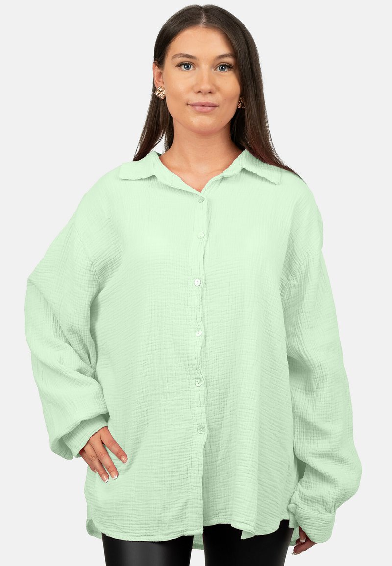 Camicia button-up verde chiaro con tessuto strutturato, dotata di colletto, maniche lunghe e vestibilità rilassata. Dettagli dei bottoni classici visibili.