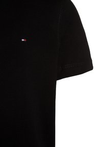 Schwarzes Kurzarm-T-Shirt aus Baumwolle, mit einem kleinen Logo in Rot, Weiß und Blau auf der Brust und sichtbaren Nähdetails.