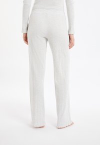 Lichtgrijze geribbelde loungebroek met een relaxte pasvorm, voorzien van een brede tailleband en uitlopende benen. De zoom is iets rafelig.