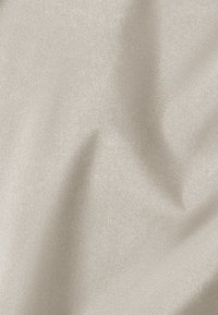 Tessuto in un leggero beige, con una texture liscia e una leggera lucentezza. Drappeggio morbido con onde e pieghe sottili, senza motivi o accessori visibili.