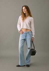 Lättvikts, vit kortärmad blus med knappar; slitna ljusblå vida jeans; svart väska; svarta platta skor med nitar; minimal textur och design.