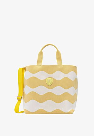 Gele en witte canvas draagtas met golvende strepen, twee korte handgrepen en een verstelbare gele schouderriem, met een klein embleem aan de voorkant.