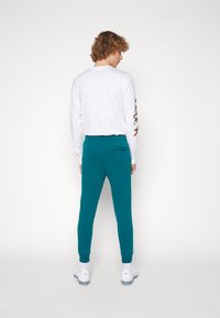 Nike Sportswear CLUB JGGR - Tracksuit bottoms - geode teal/white