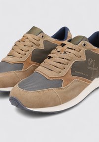 Zapatillas deportivas en beige y gris con materiales de ante y malla, que presentan cordones, acentos del logo y una suela texturizada para agarre y soporte.