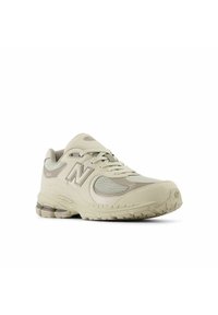 Scarpa sportiva beige con collo imbottito, dettagli in rete e suola in gomma dotata di tecnologia assorbente degli urti e motivi testurizzati.