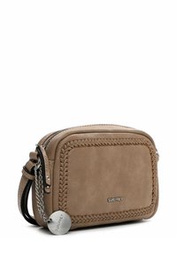 Borsa a spalla in pelle marrone chiaro con dettagli intrecciati, hardware in argento, chiusura con zip e un'etichetta rotonda con logo attaccata a una catena decorativa.