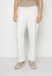 Pantalones de algodón blancos con un diseño de pierna recta, que cuentan con cierre de botón de metal, dos bolsillos laterales y un acabado texturizado sutil.